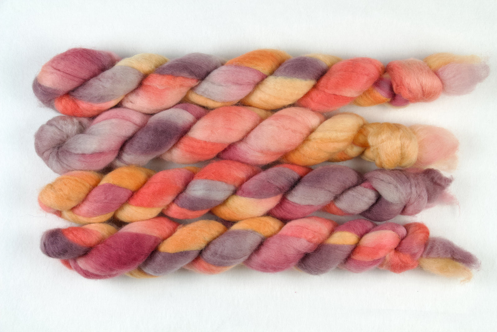 Braided fiber skein with pink, purple, and orange on a white background