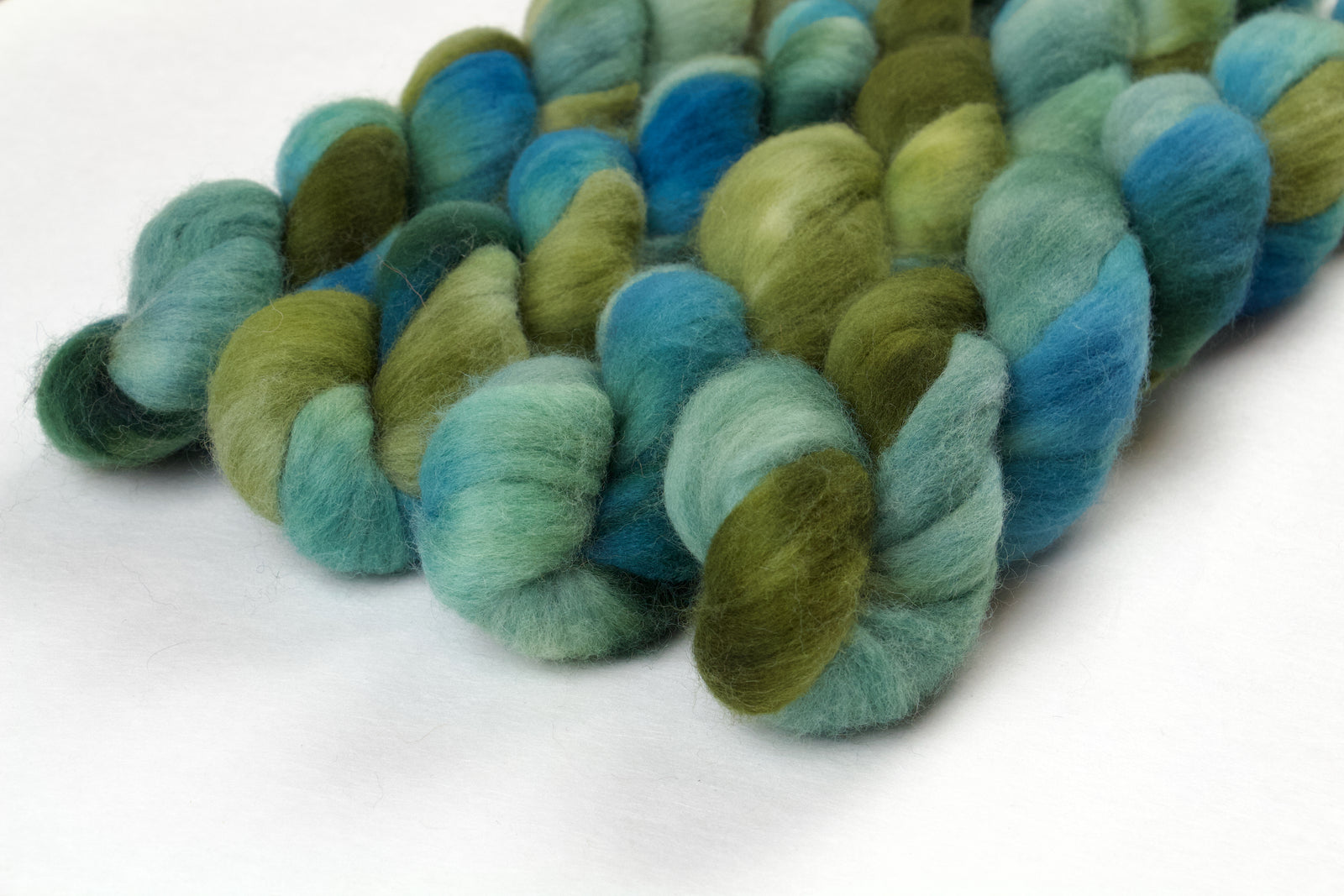 Braided fiber skein with green and blue gradient on a white background