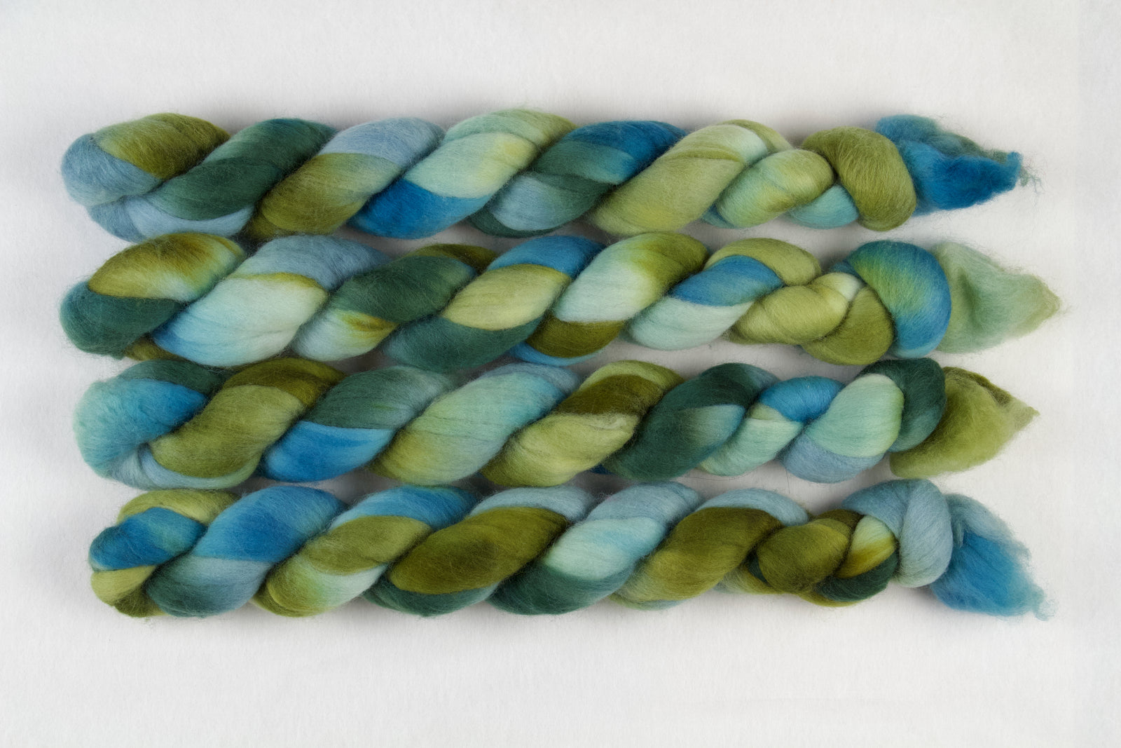 Braided fiber skein with green and blue gradient on a white background