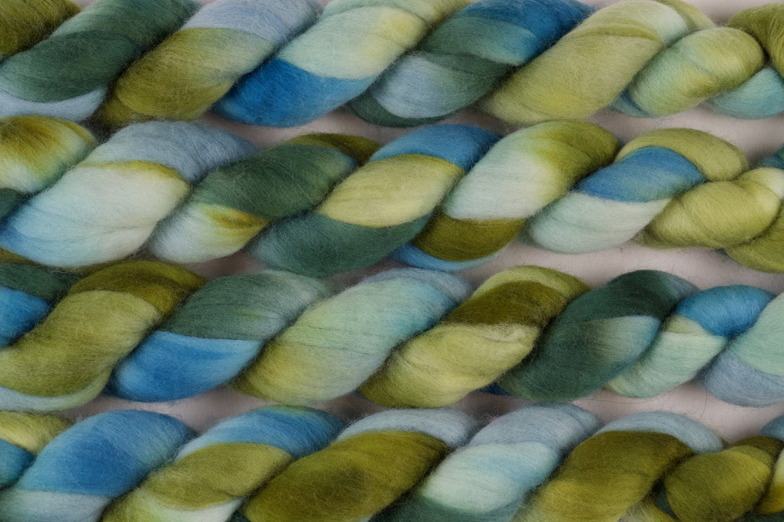 Braided fiber skein with green and blue gradient on a white background