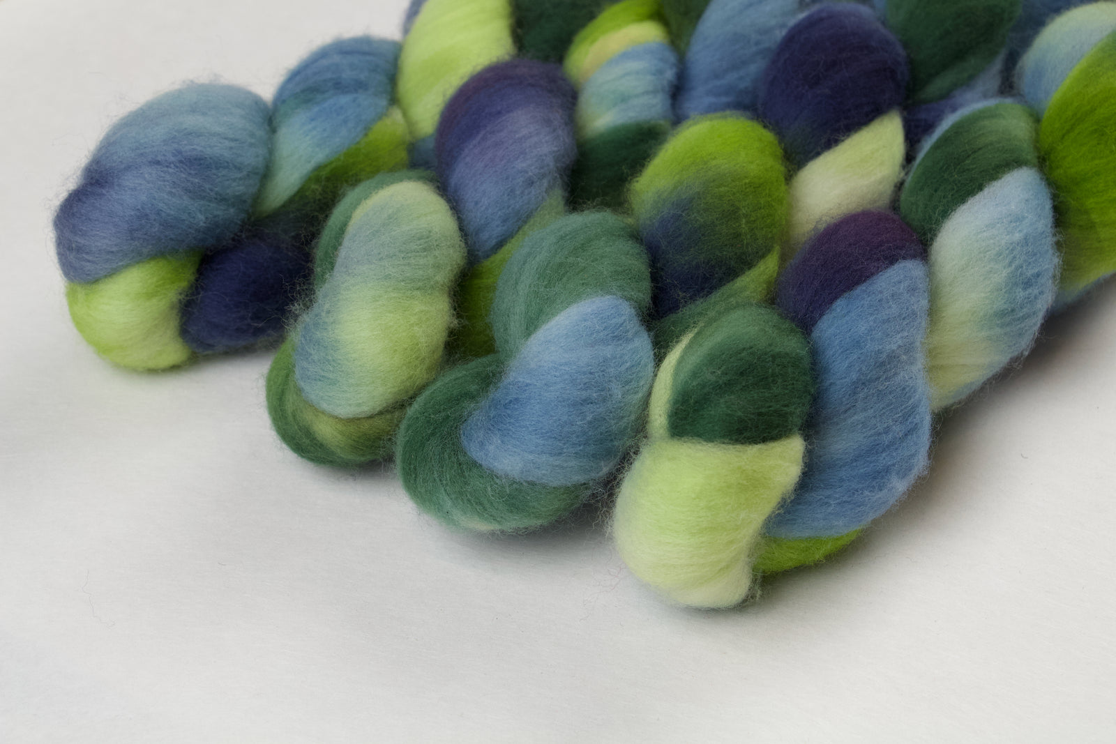Braided fiber skein with green and blue on a white background