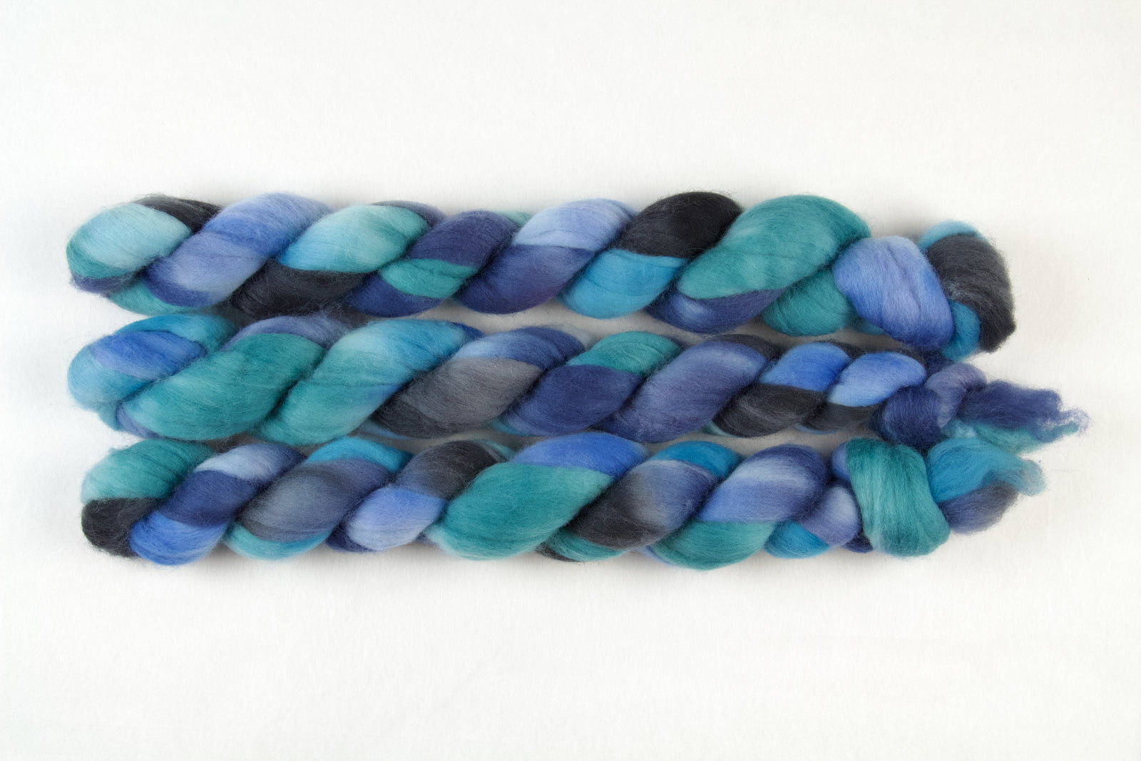 Braided fiber skein with blue, green, and grey on a white background
