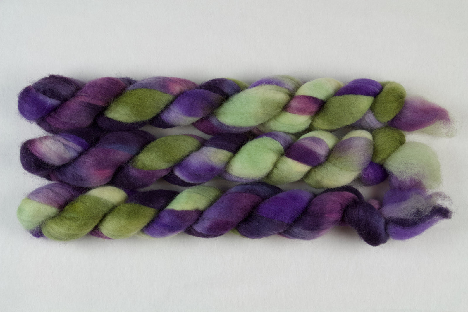 Braided fiber skein with purple and green on a white background