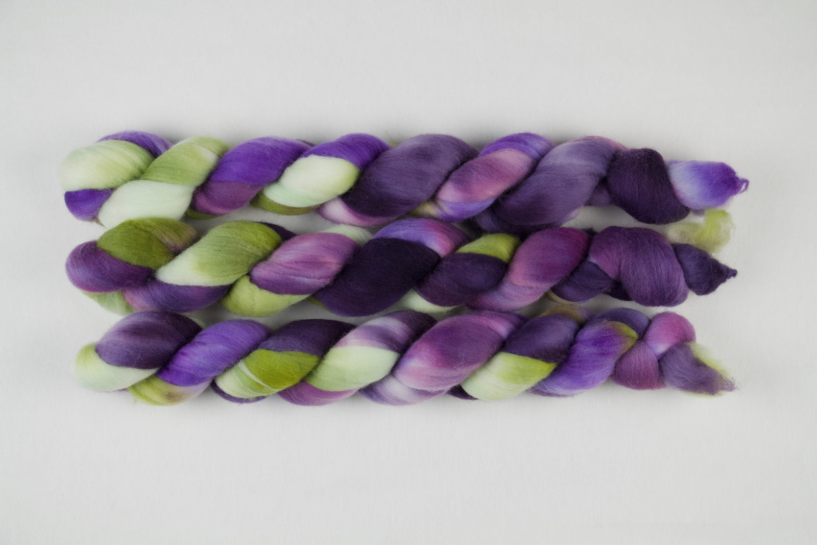 Braided fiber skein with purple and green on a white background