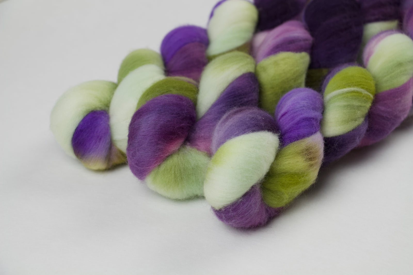 Braided fiber skein with purple and green on a white background