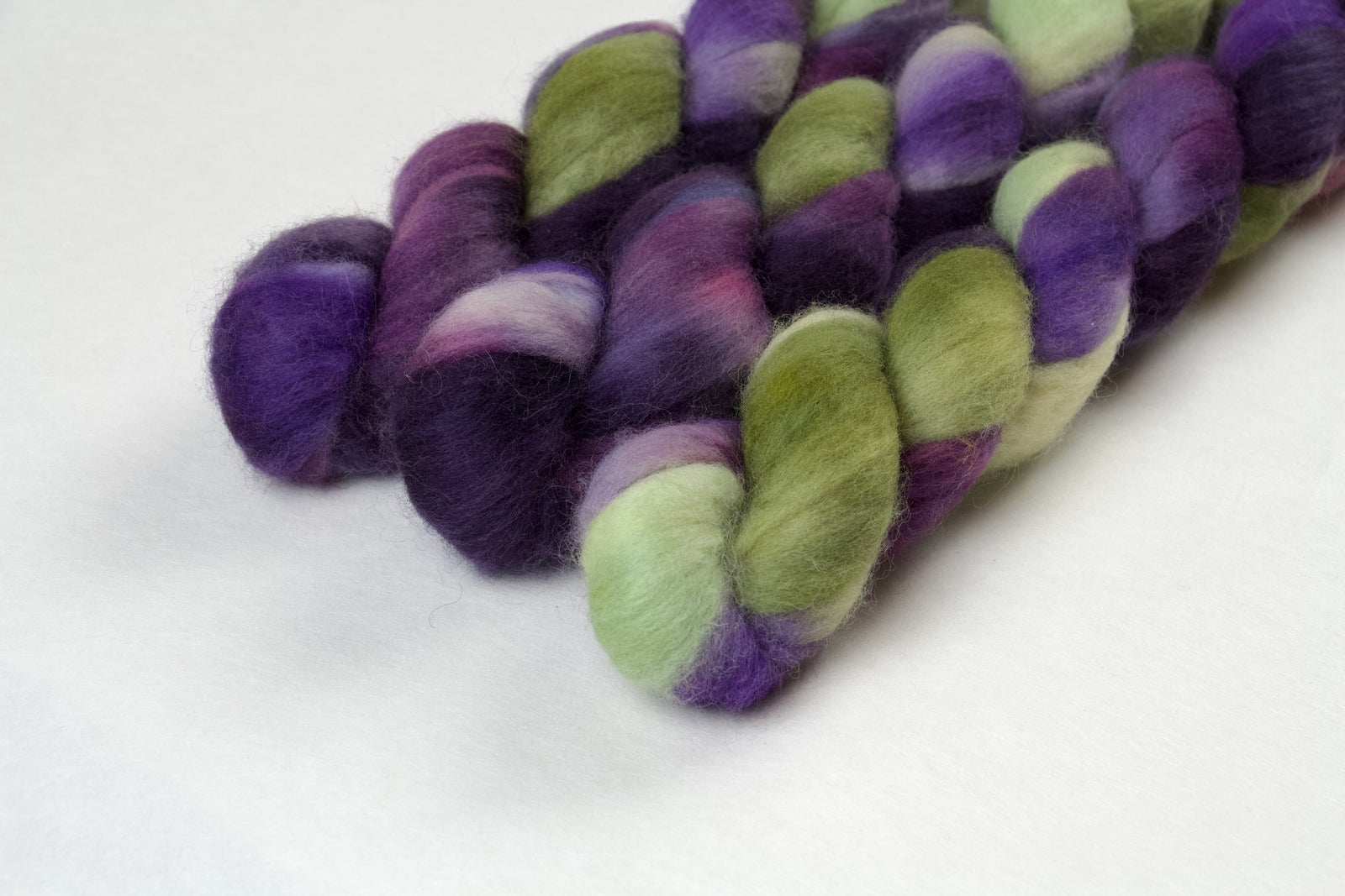 Braided fiber skein with purple and green on a white background