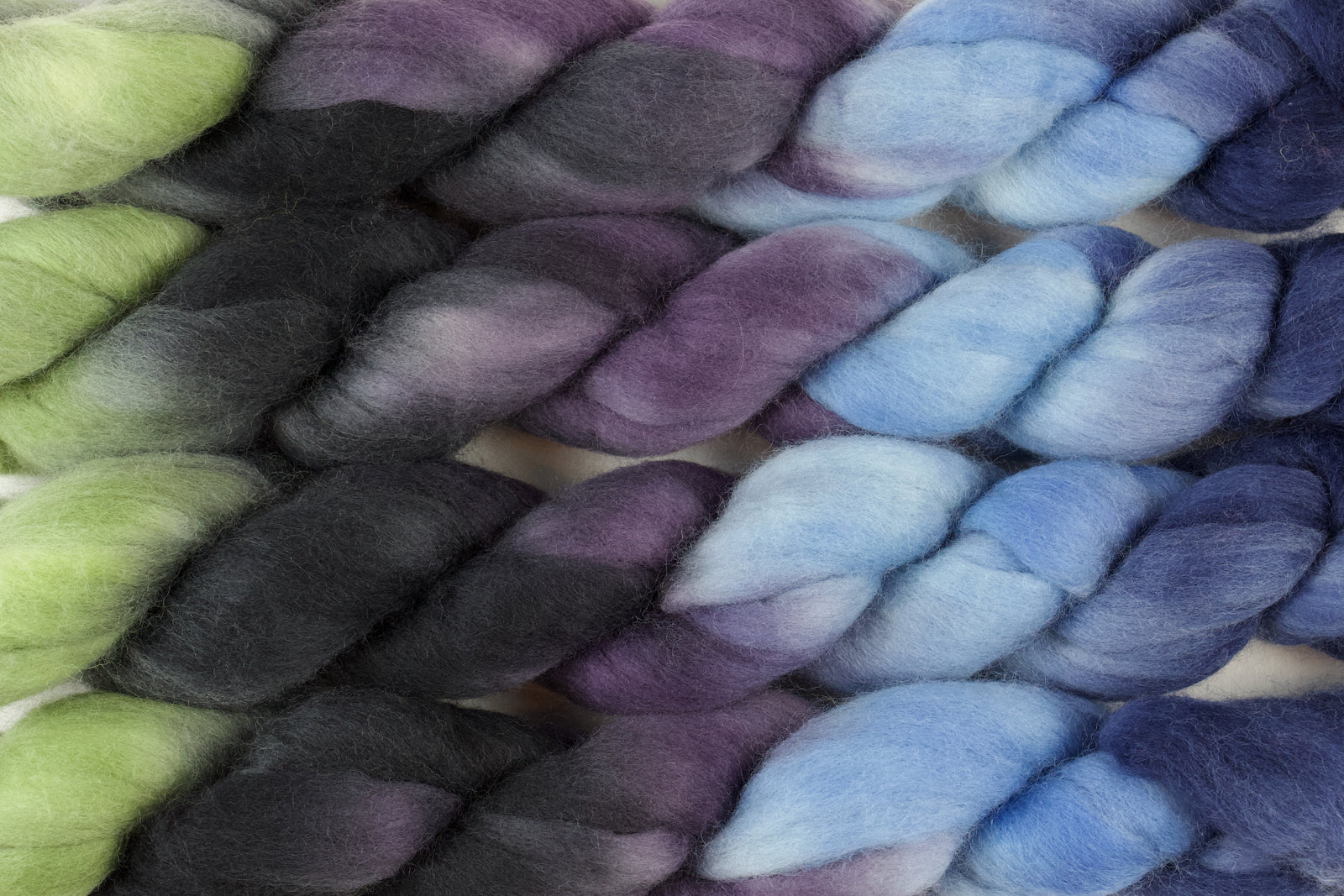 Braided fiber skein with blue, purple, black, and green on a white background