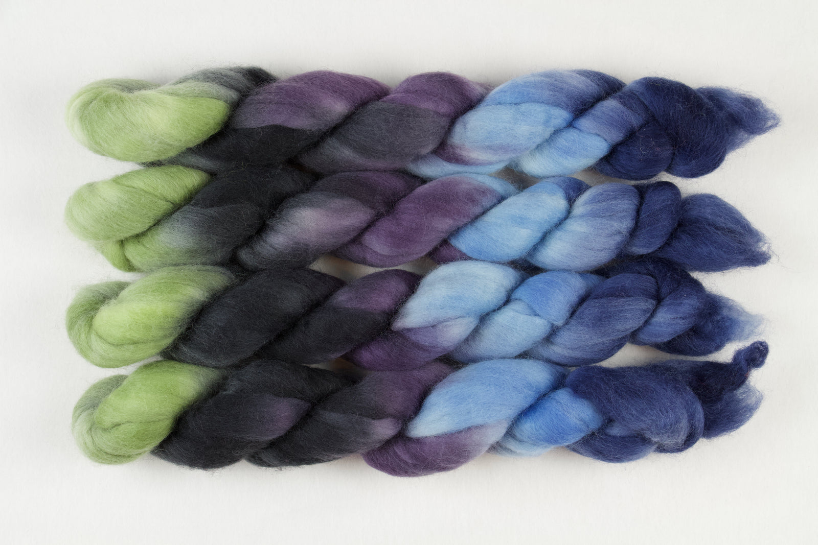 Braided fiber skein with blue, purple, black, and green on a white background