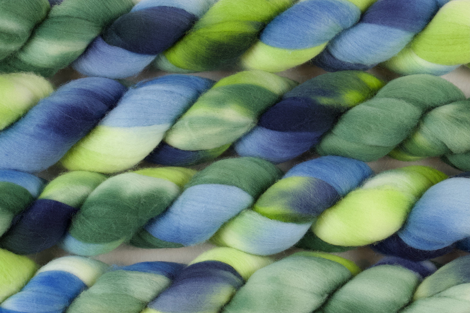 Braided fiber skein with green and blue on a white background