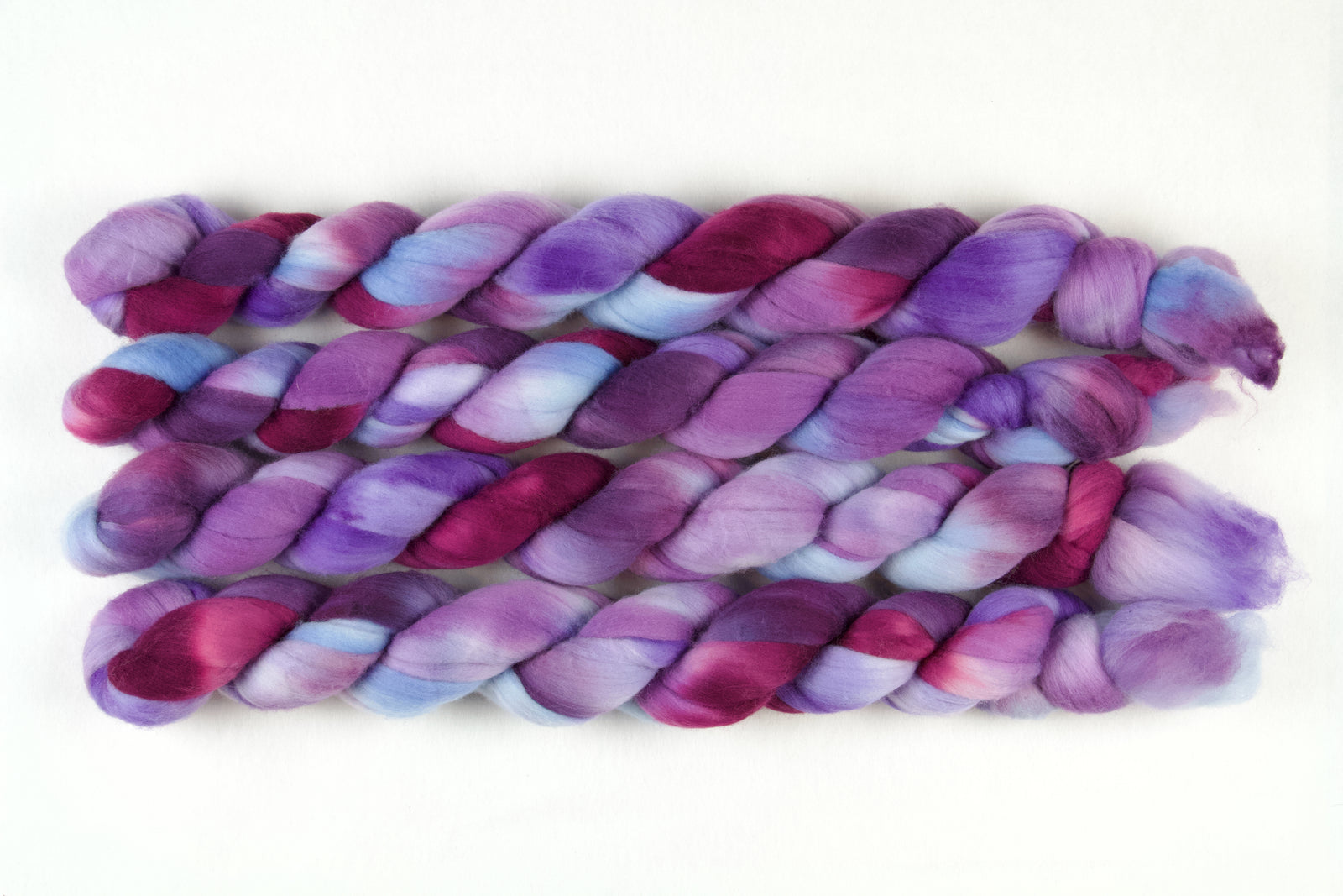 Braided fiber skein with blue, purple, and pink on a white background