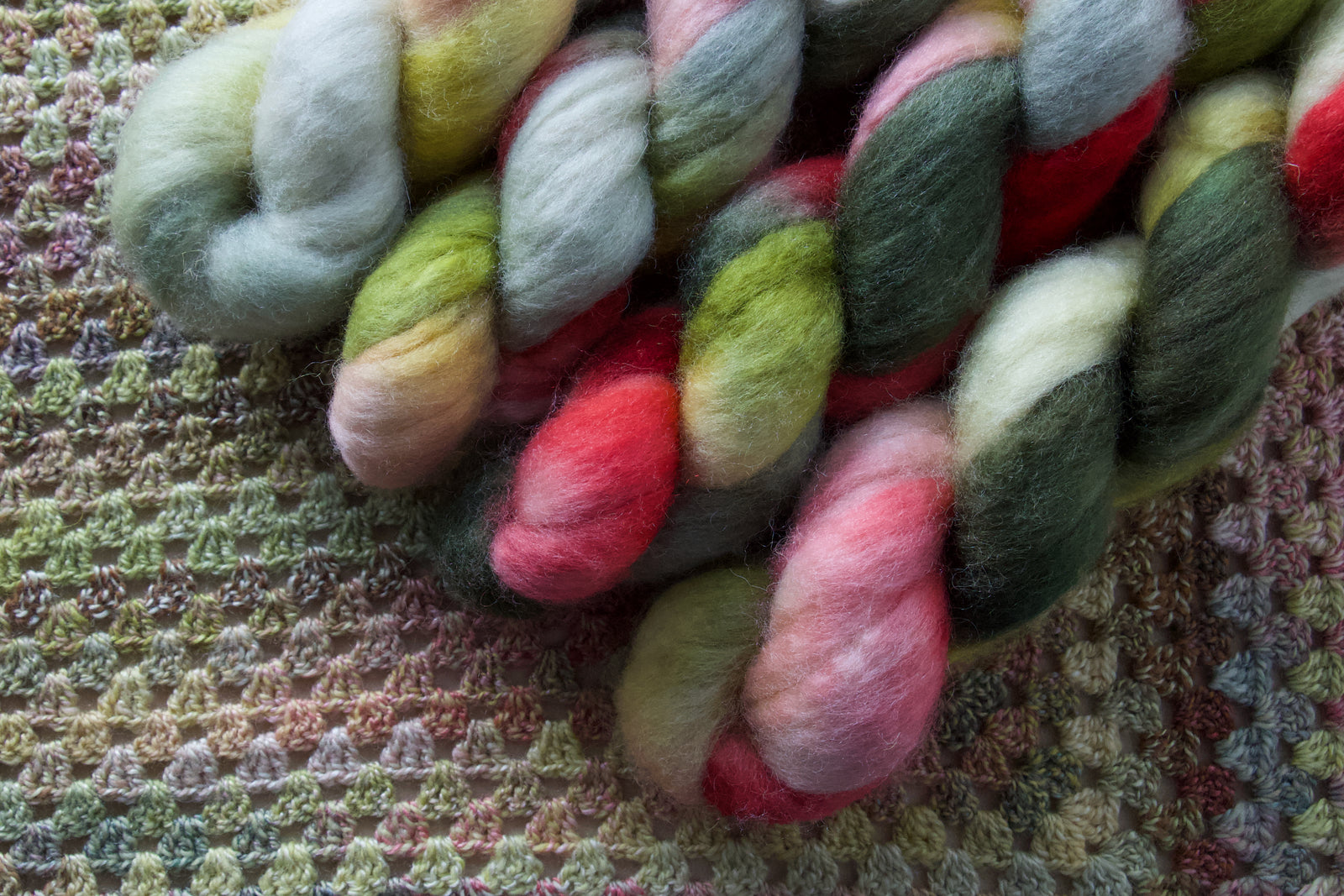 Colorful fiber skeins on a crocheted fabric background
