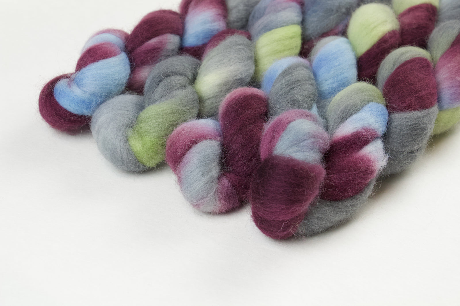 Braided fiber skein with blue, red, gray, and green on a white background