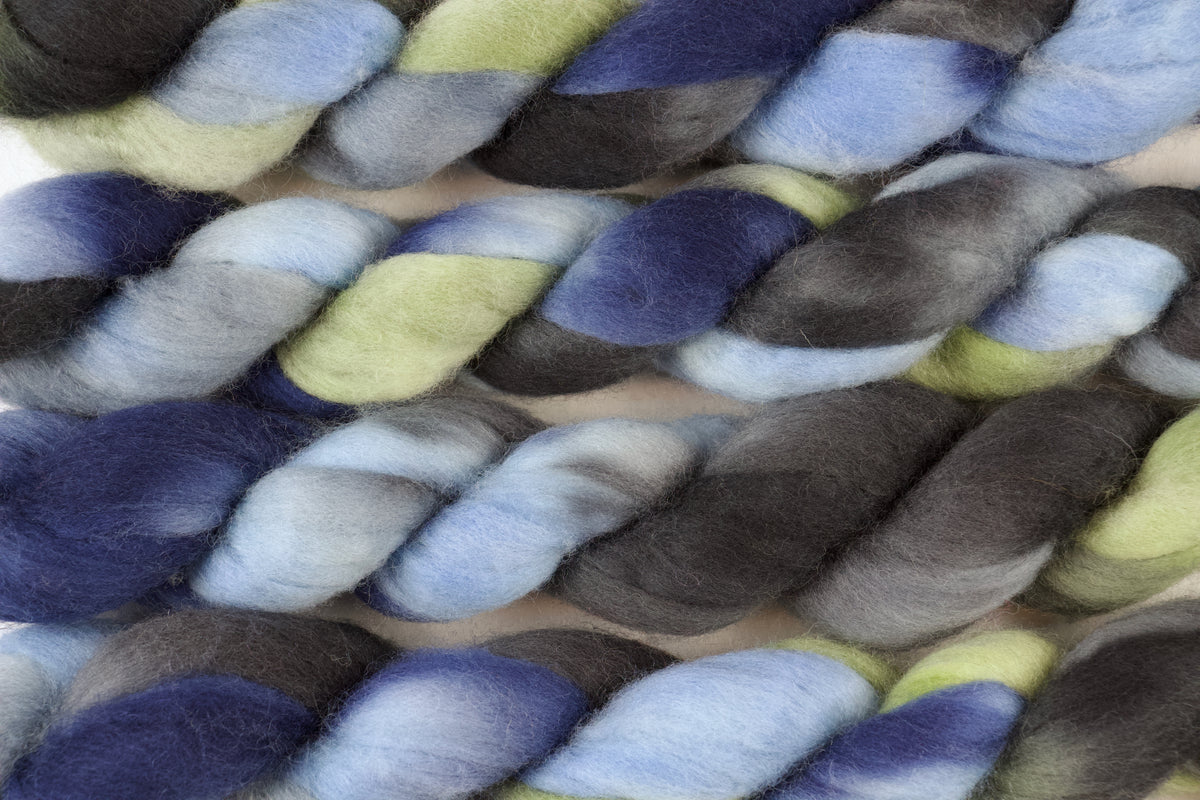Braided fiber skein with blue, gray, and green on a white background