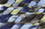 Braided fiber skein with blue, gray, and green on a white background