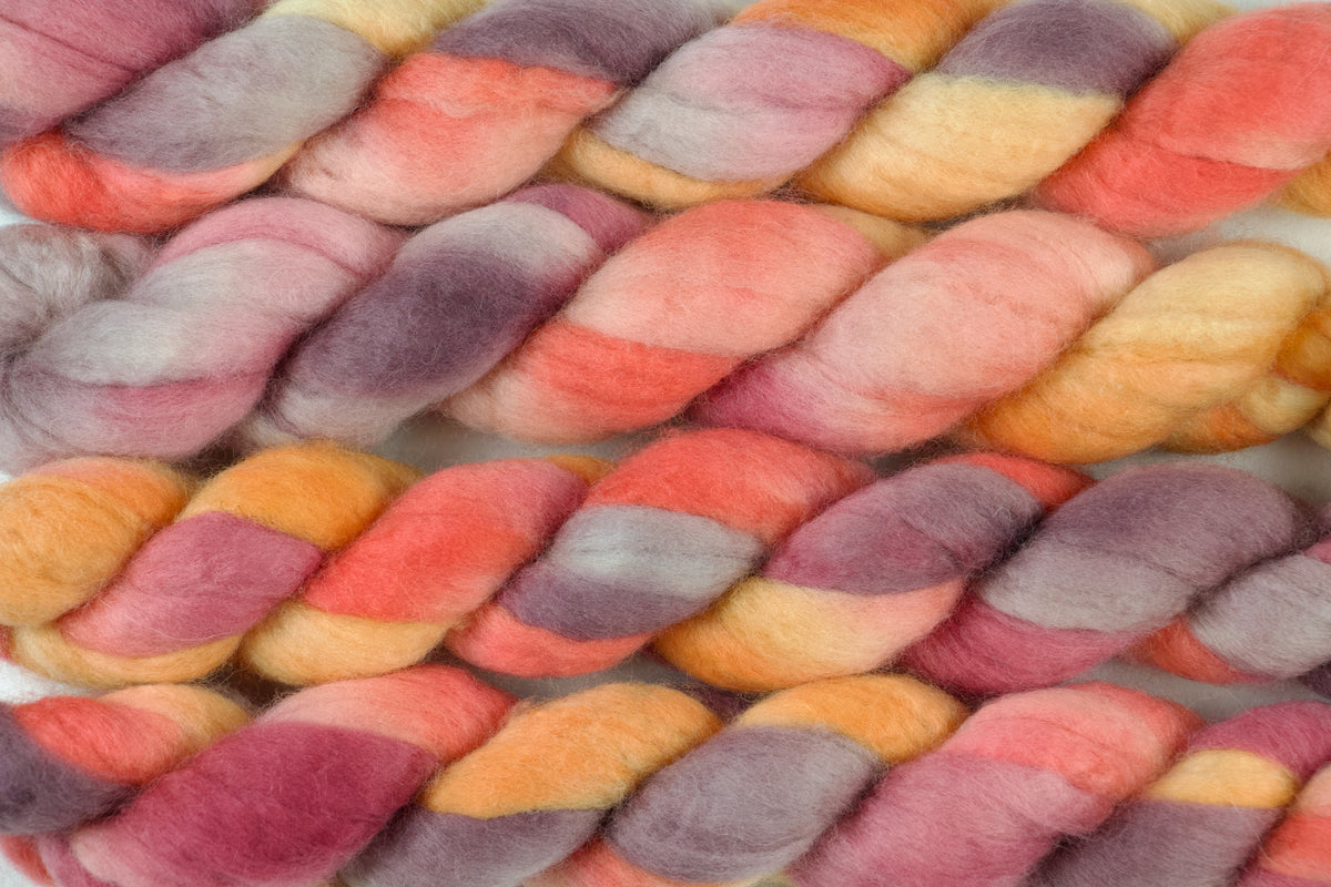 Braided fiber skein with pink, purple, and orange on a white background