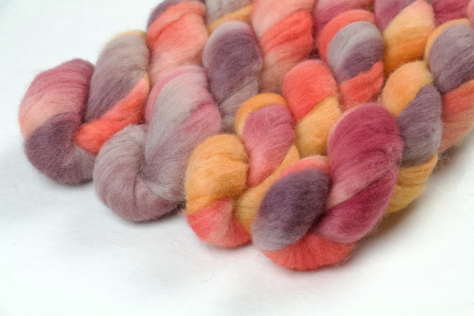 Braided fiber skein with pink, purple, and orange on a white background