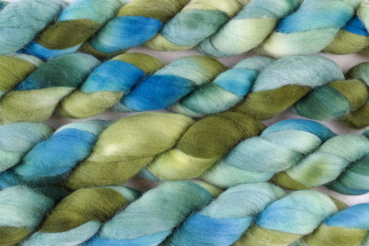 Braided fiber skein with green and blue gradient on a white background