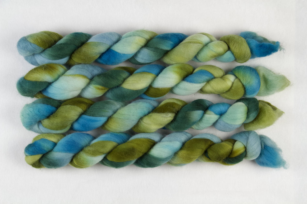 Braided fiber skein with green and blue gradient on a white background