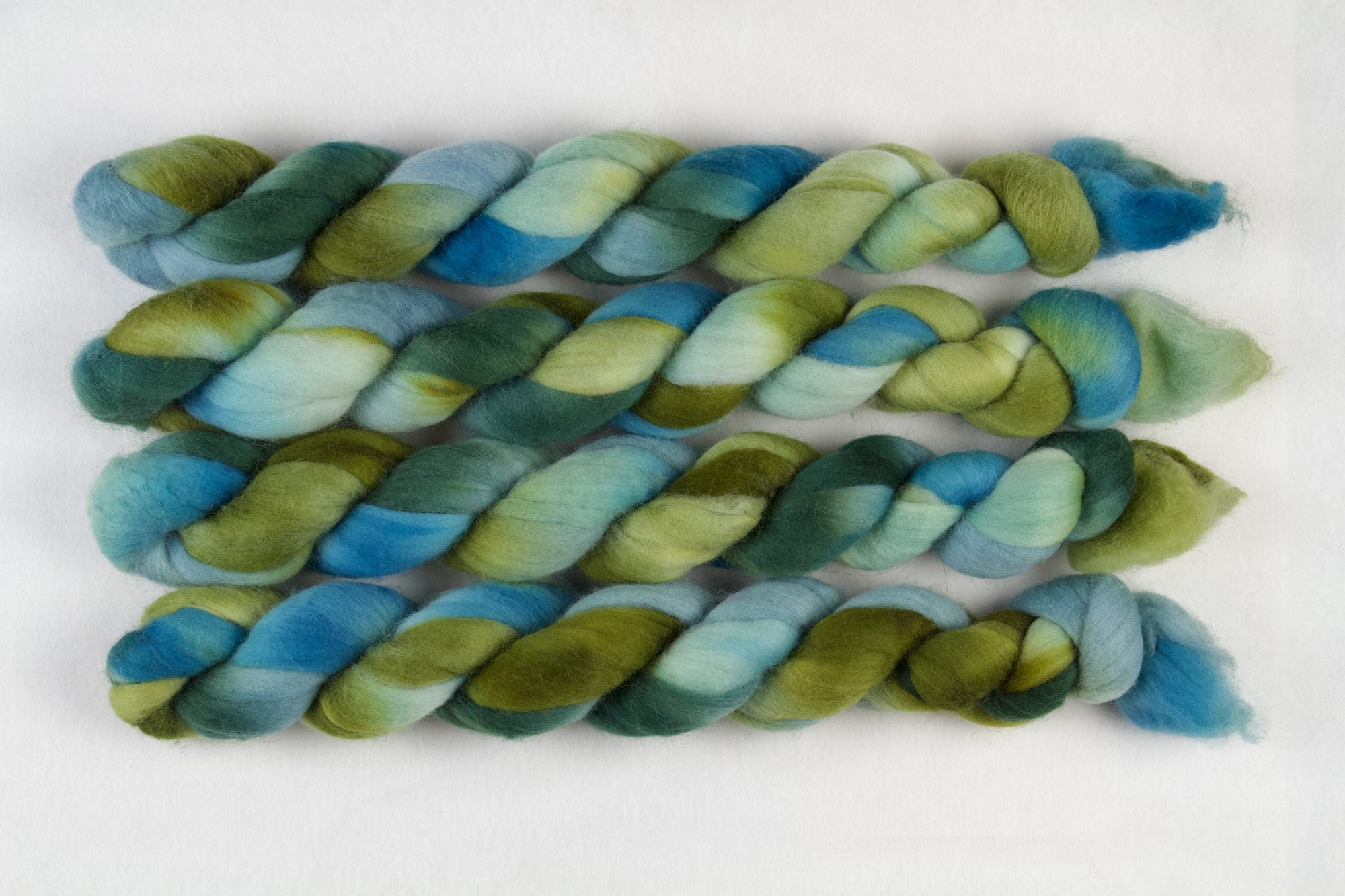 Braided fiber skein with green and blue gradient on a white background