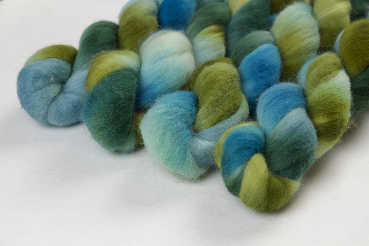 Braided fiber skein with green and blue gradient on a white background