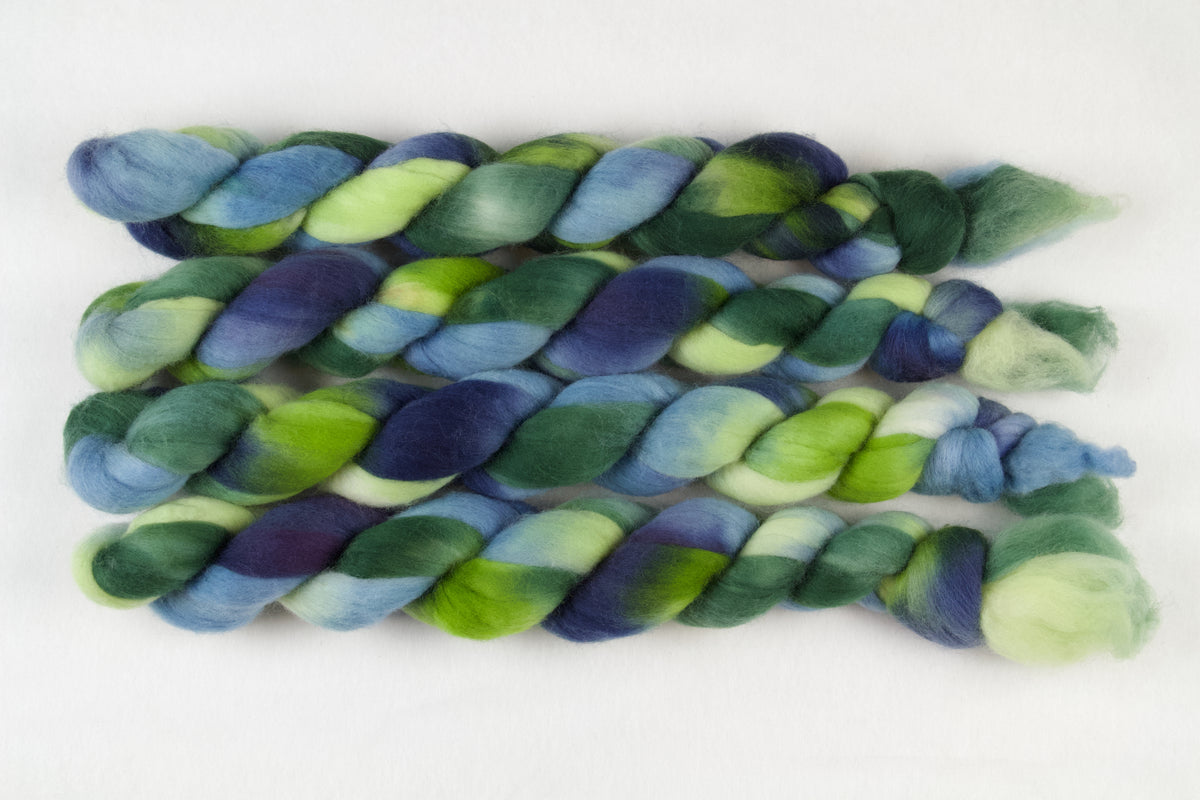 Braided fiber skein with green and blue on a white background