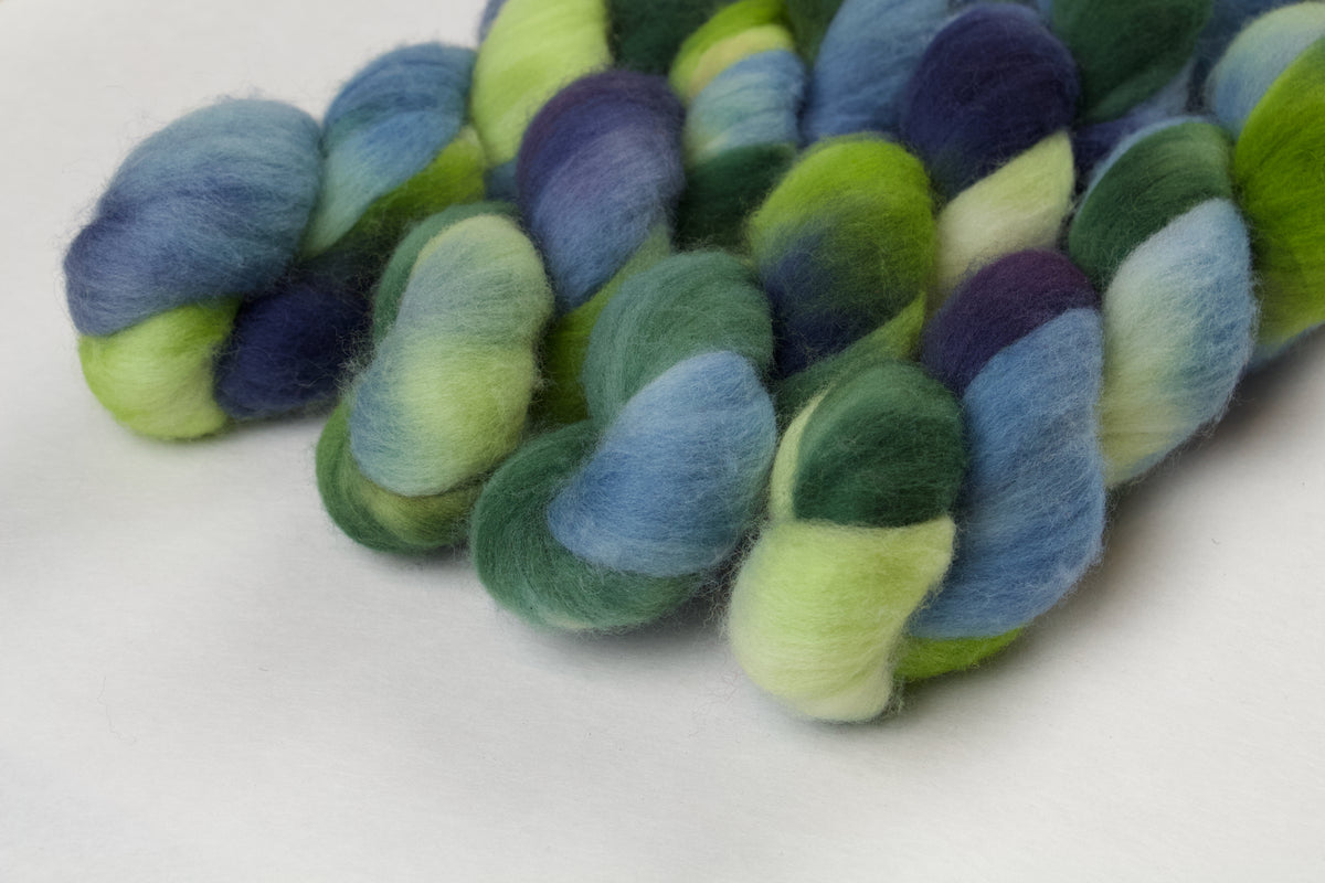 Braided fiber skein with green and blue on a white background
