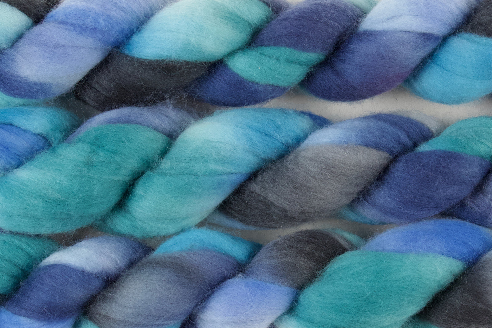 Braided fiber skein with blue, green, and grey on a white background