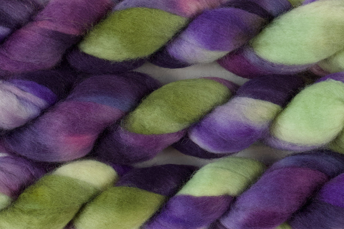 Braided fiber skein with purple and green on a white background