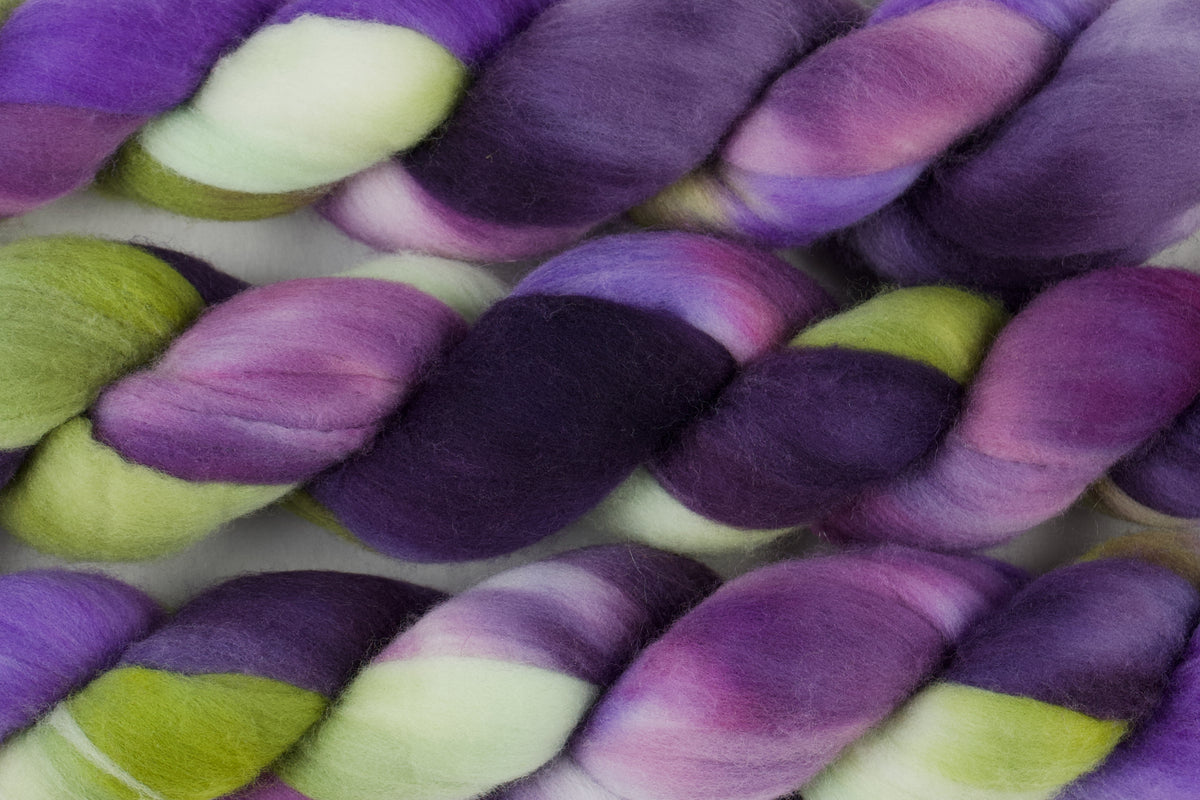 Braided fiber skein with purple and green on a white background