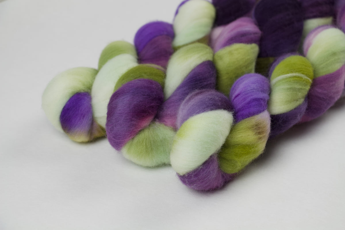 Braided fiber skein with purple and green on a white background