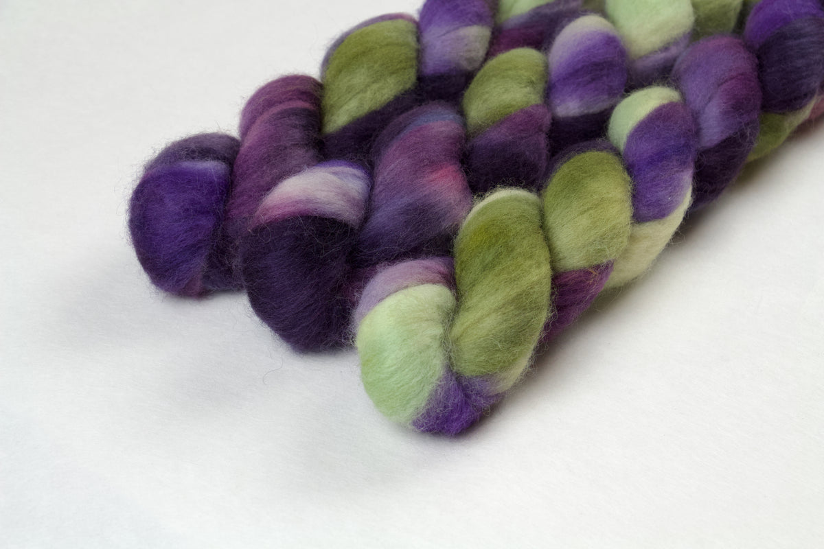 Braided fiber skein with purple and green on a white background