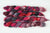 Braided fiber skein with pink, red, and black on a white background