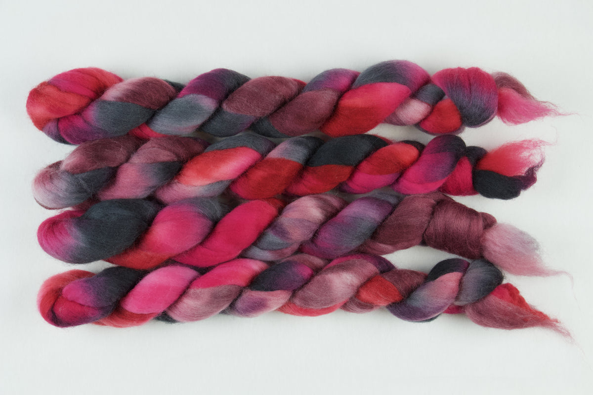 Braided fiber skein with pink, red, and black on a white background