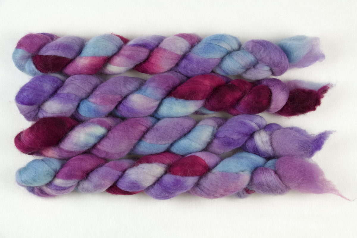 Braided fiber skein with blue, purple, and pink on a white background