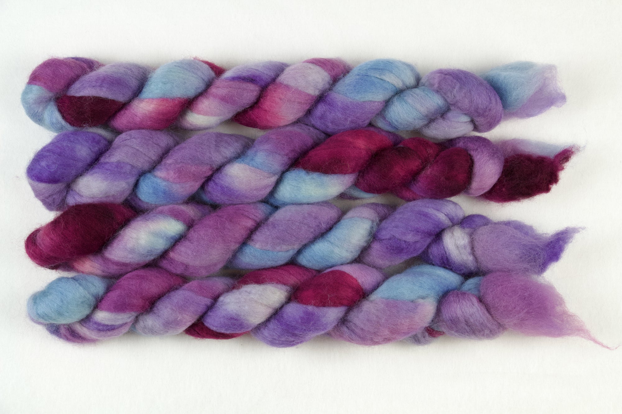 Braided fiber skein with blue, purple, and pink on a white background