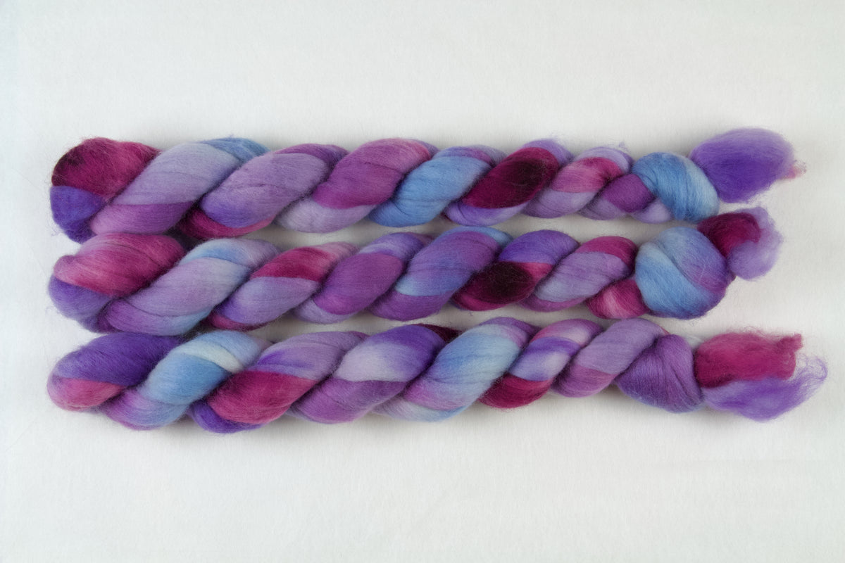 Braided fiber skein with blue, purple, and pink on a white background