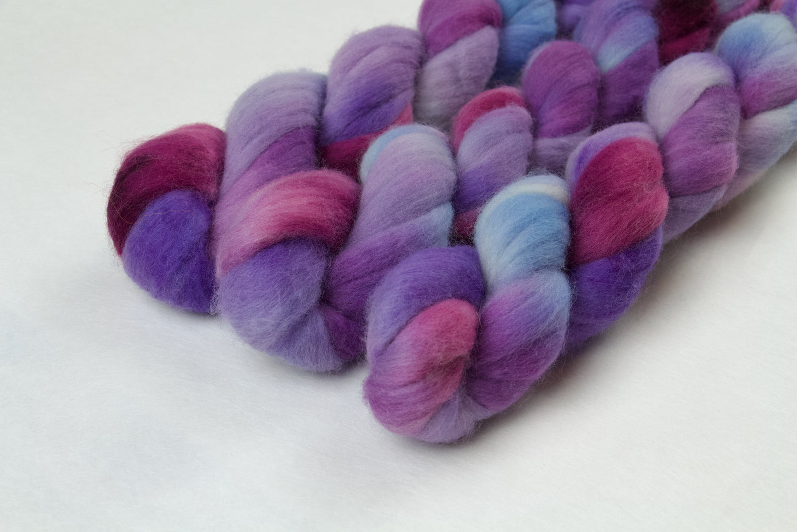 Braided fiber skein with blue, purple, and pink on a white background