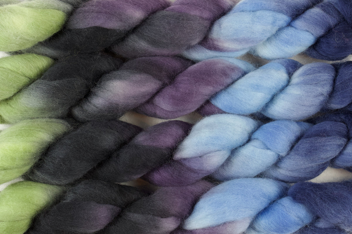 Braided fiber skein with blue, purple, black, and green on a white background