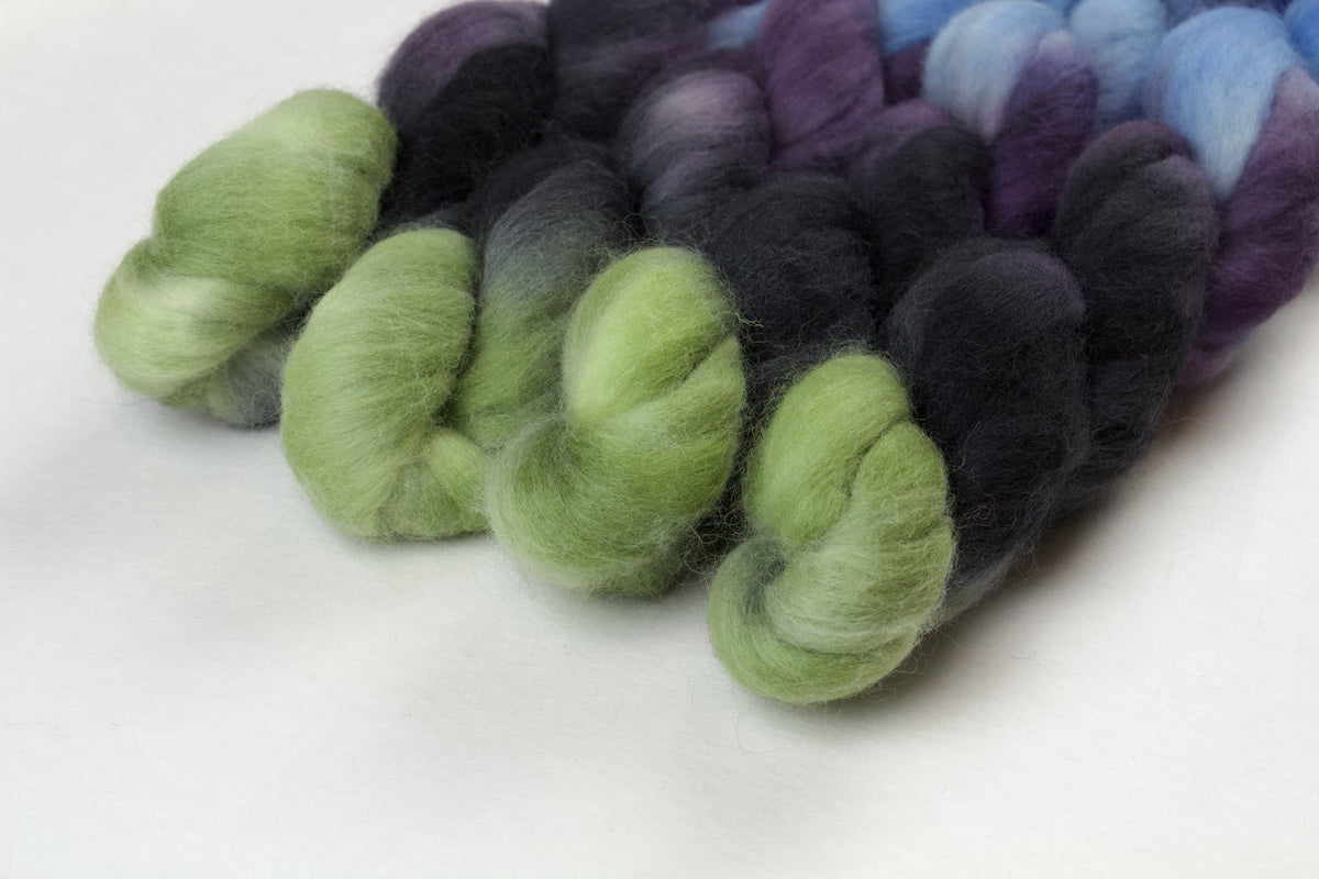 Braided fiber skein with blue, purple, black, and green on a white background
