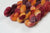 Braided fiber skein with red, orange, gold, and purple on a white background