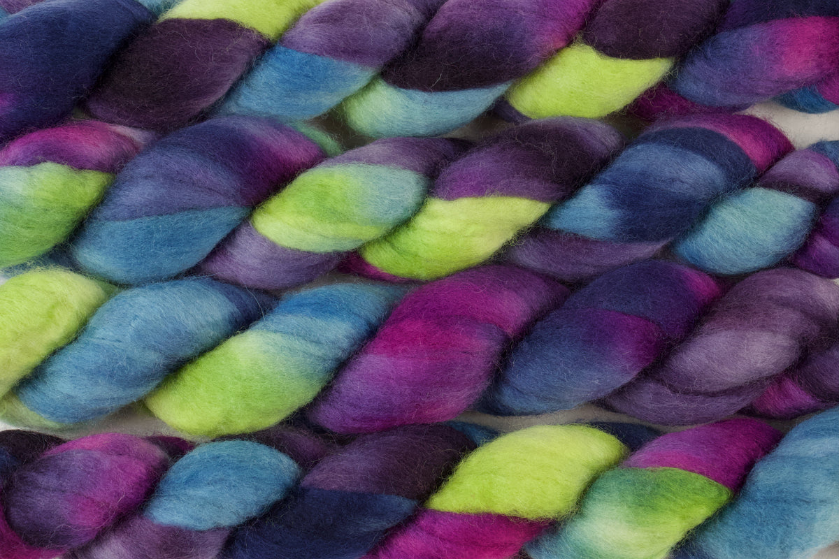 Braided fiber skein with blue, purple, pink, and green on a white background