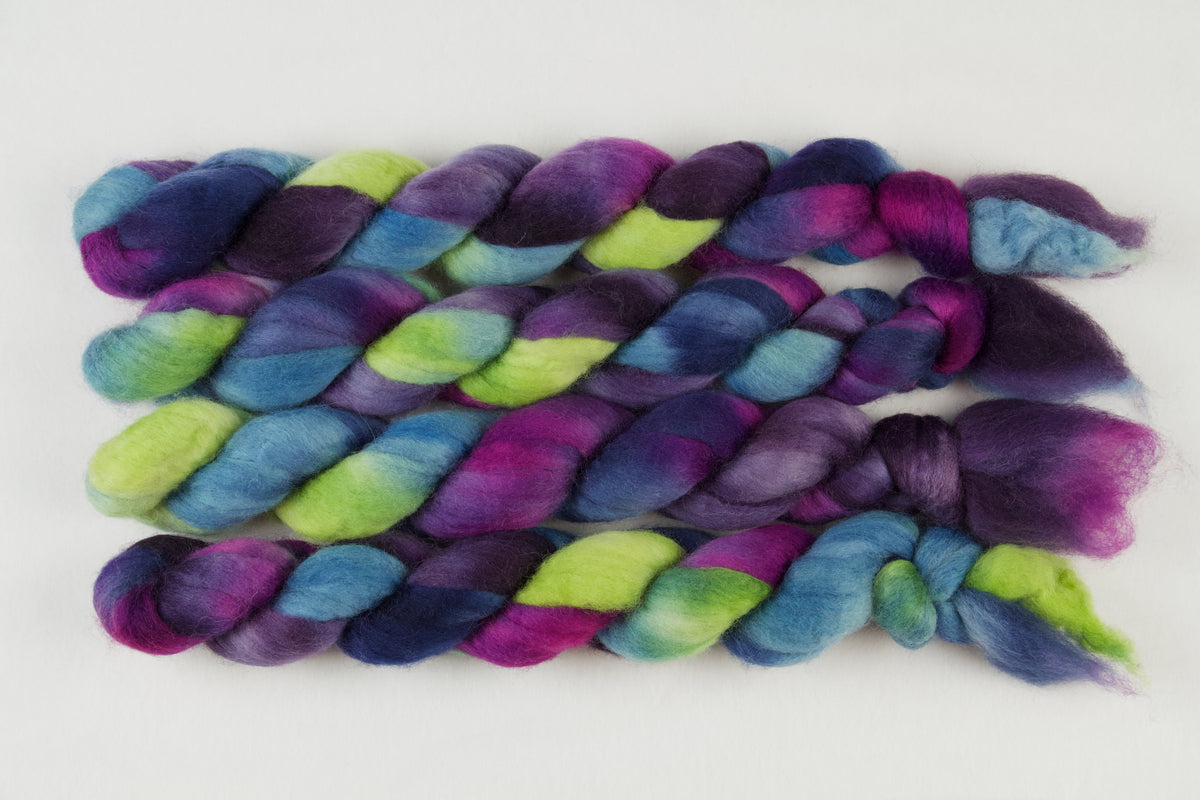 Braided fiber skein with blue, purple, pink, and green on a white background