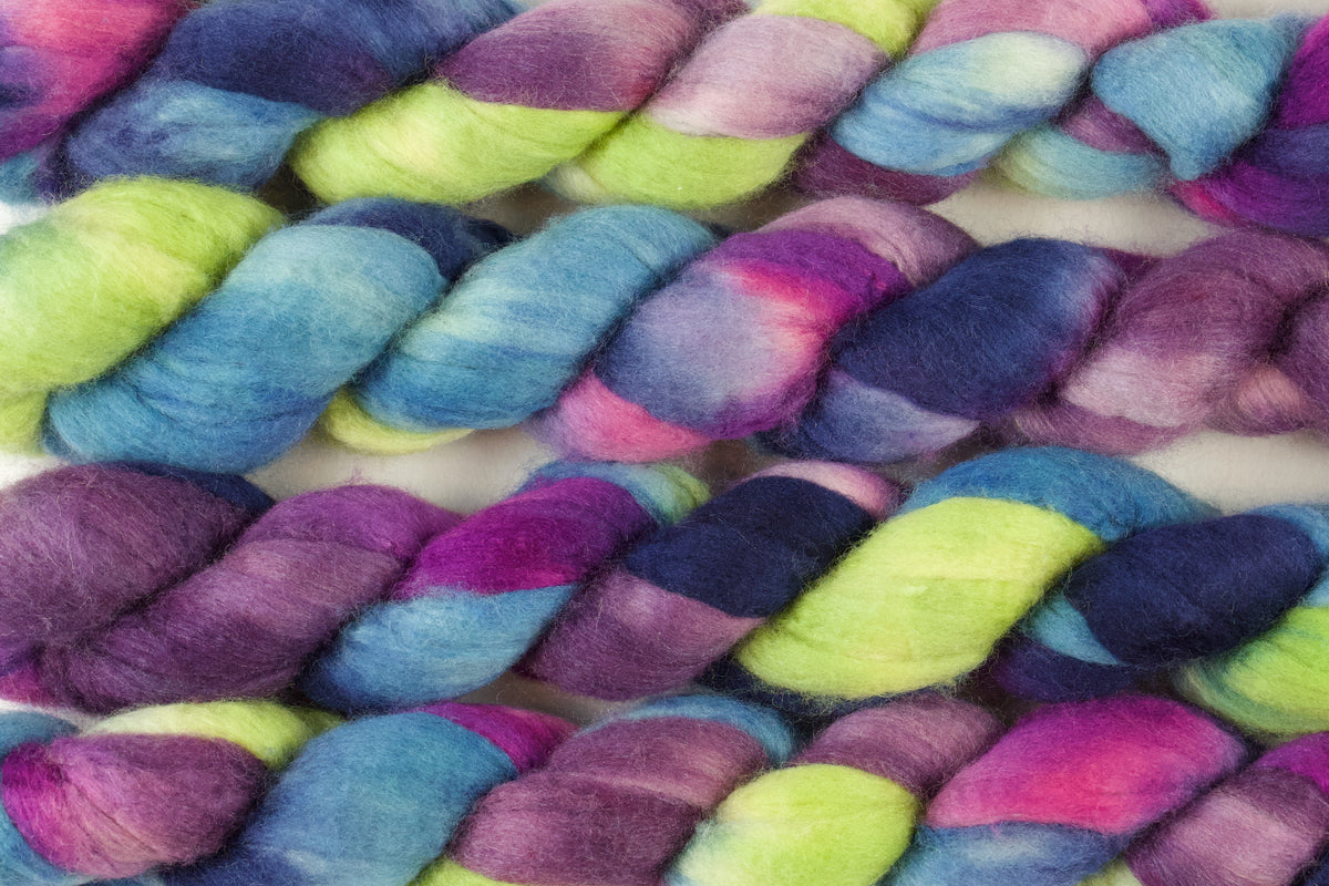Braided fiber skein with blue, purple, pink, and green on a white background