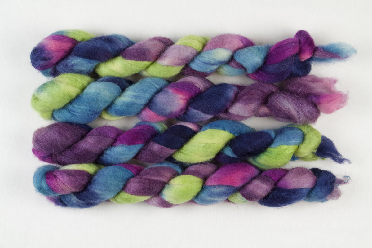 Braided fiber skein with blue, purple, pink, and green on a white background