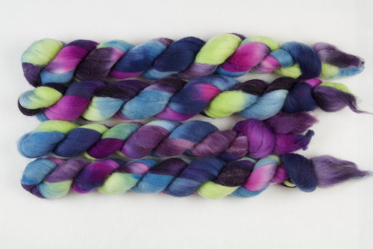 Braided fiber skein with blue, purple, pink, and green on a white background