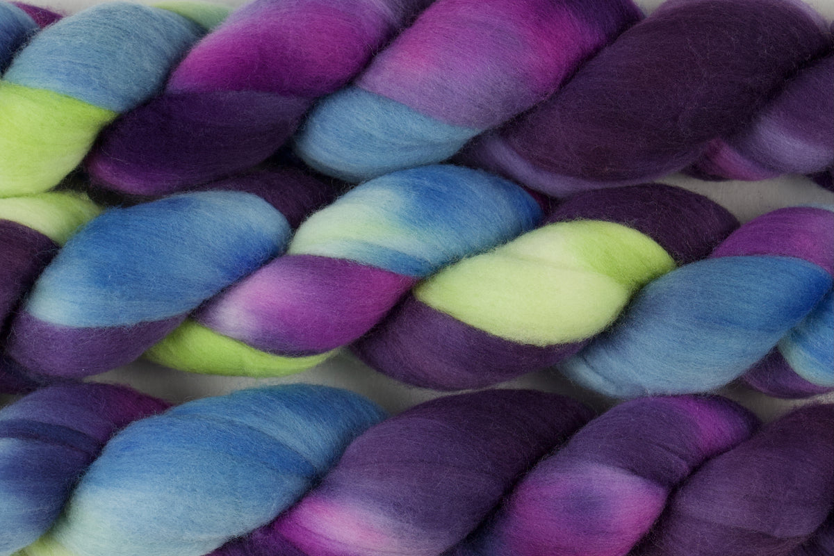 Braided fiber skein with blue, purple, pink, and green on a white background