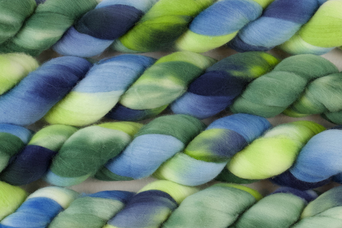 Braided fiber skein with green and blue on a white background