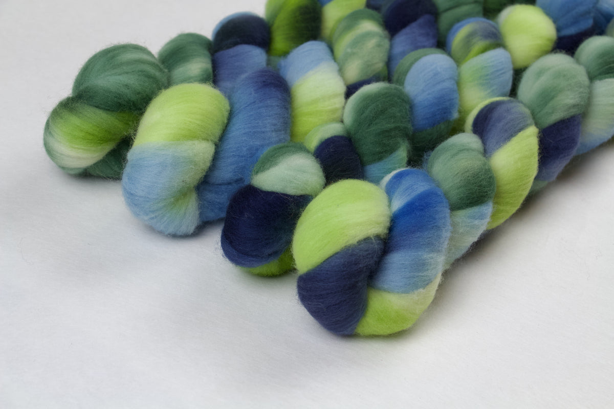 Braided fiber skein with green and blue on a white background