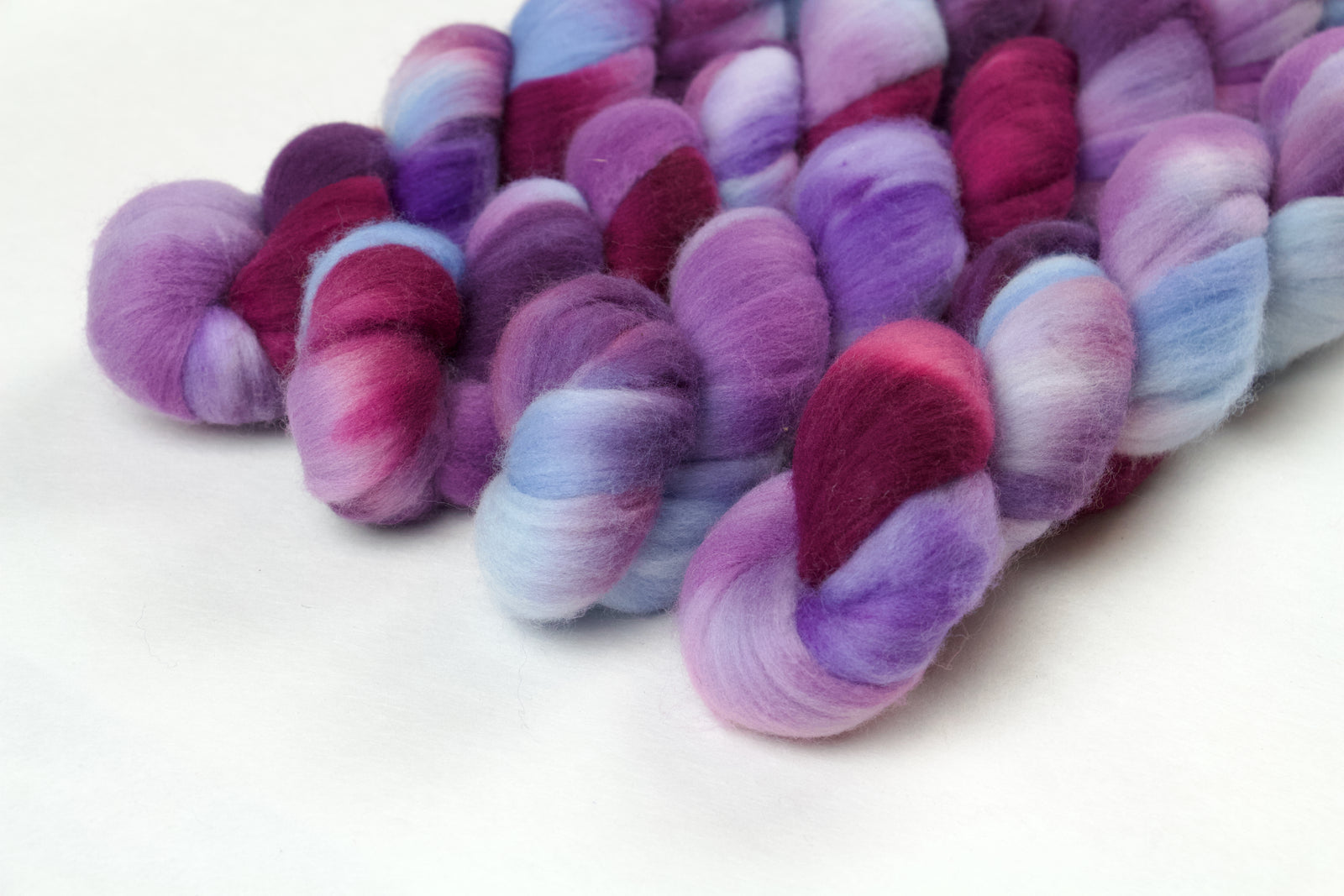 Braided fiber skein with blue, purple, and pink on a white background