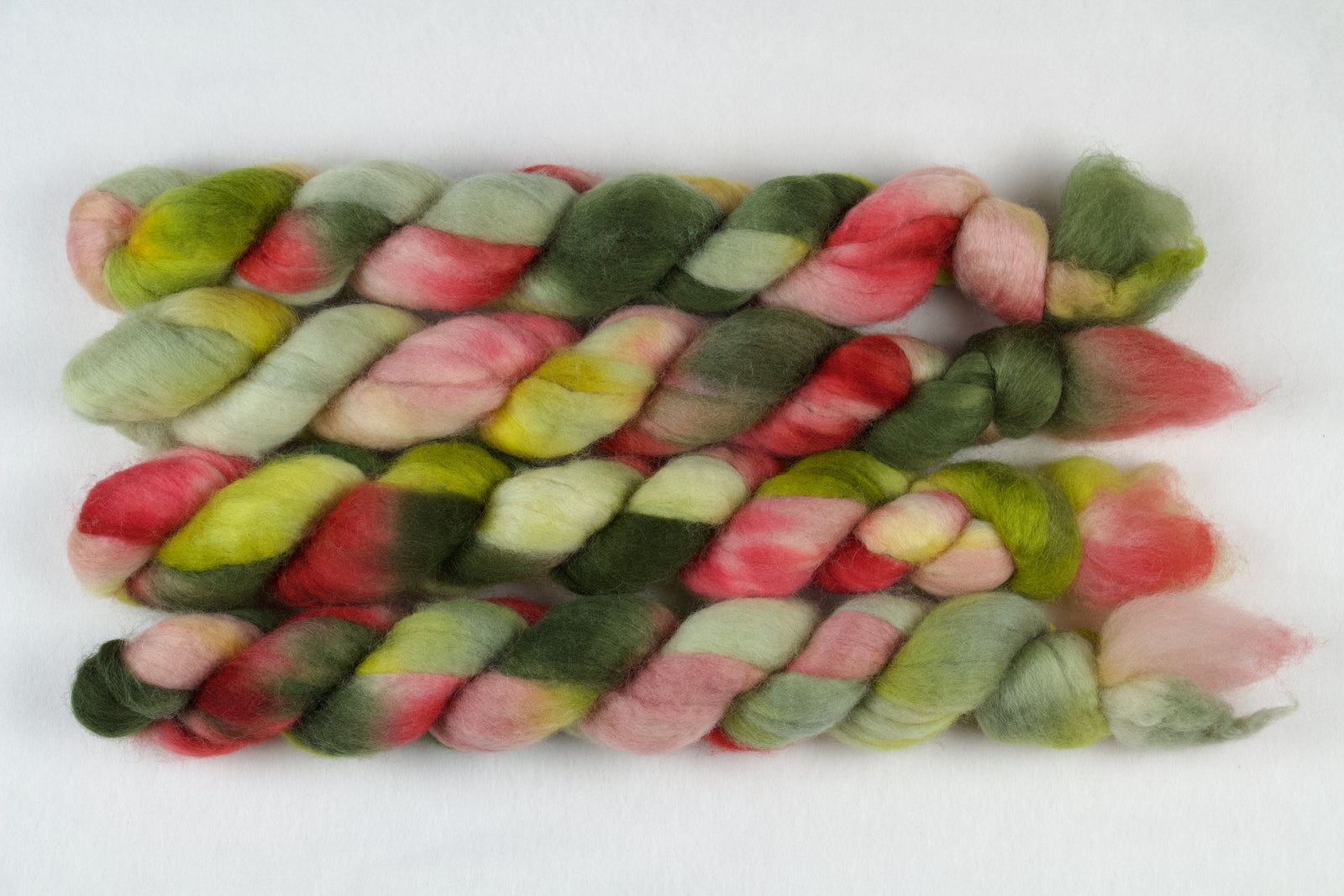 Braided fiber skein with pink, red, and green on a white background